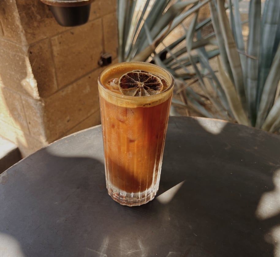 Cold drink with dried orange garnish at Cartel Coffee