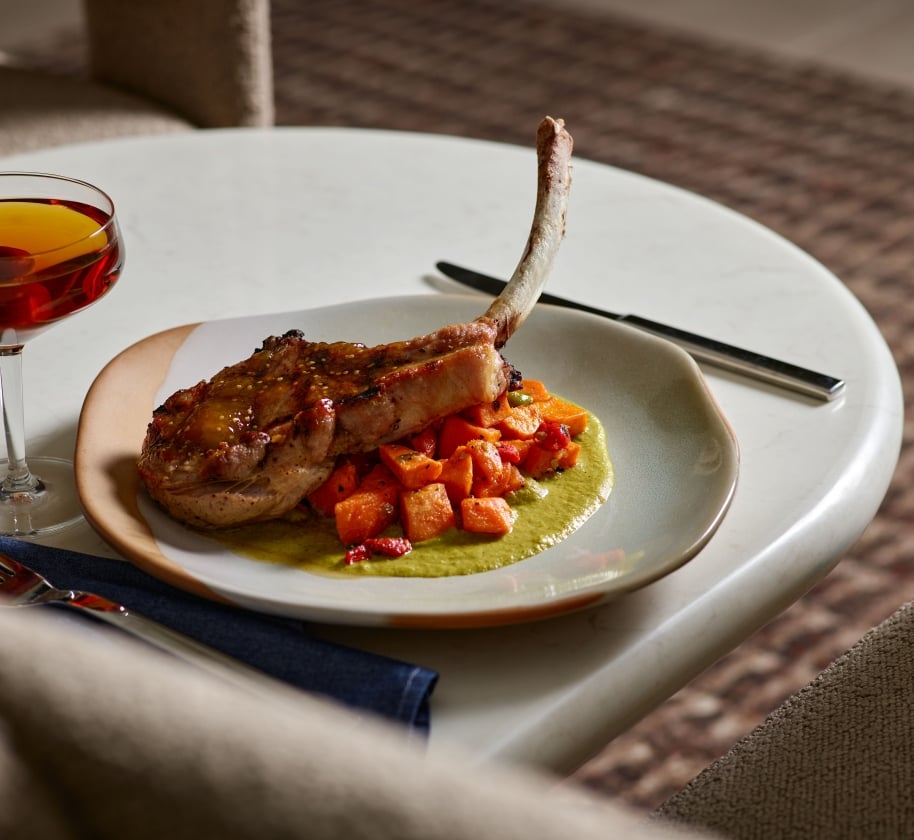 A cooked pork chop on carrots and a green sauce at Yellowbell