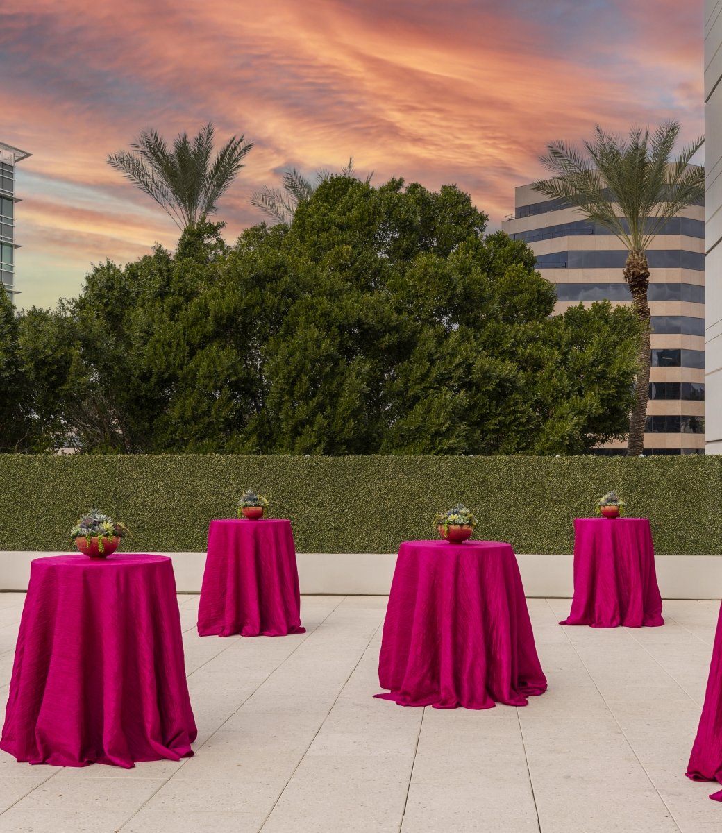 Outdoor space at sunset at the Camby with 6 round standing tables covered in pink table cloths