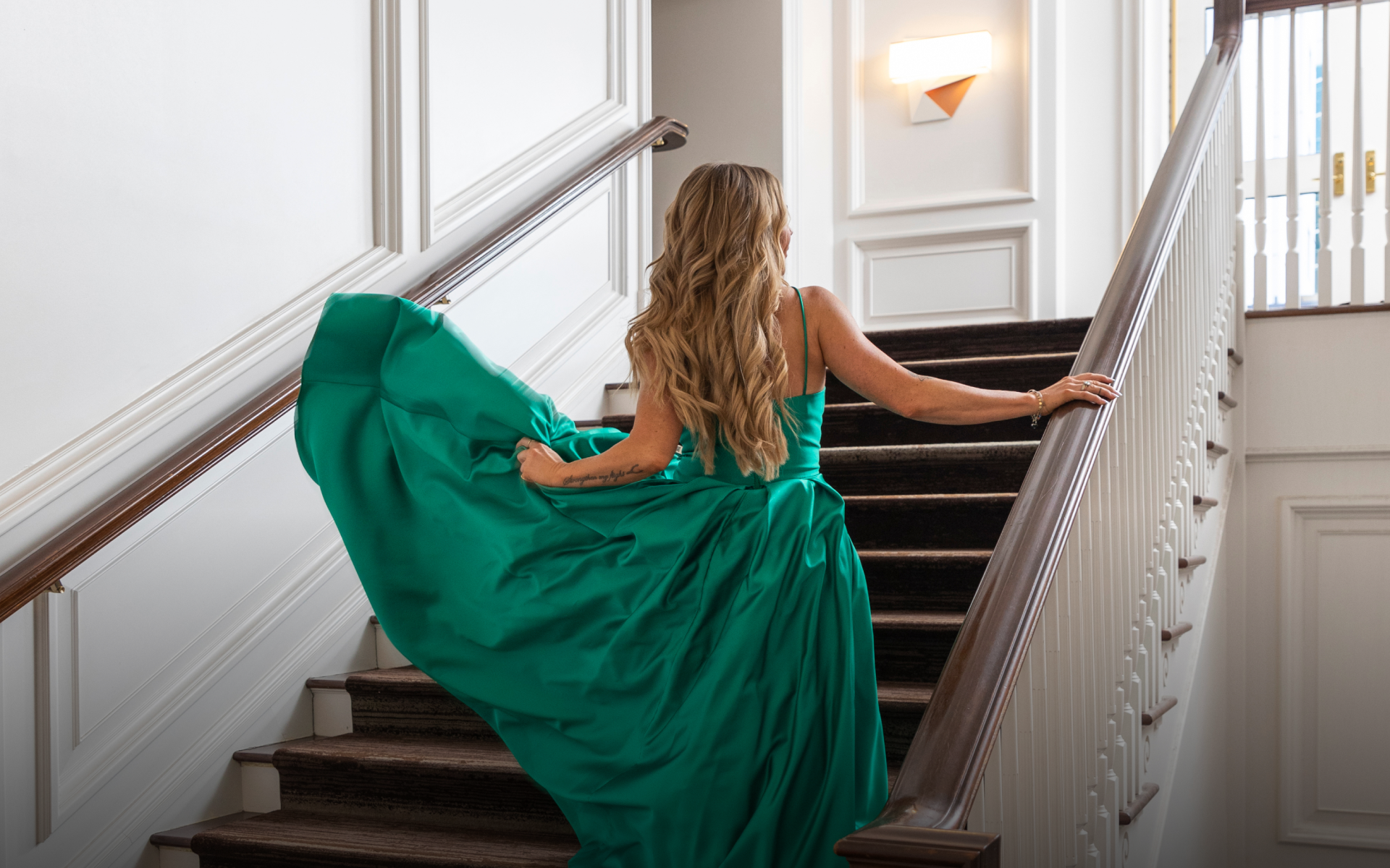 A woman walking up a flight of stairs wearing a green flowing dress at the Camby