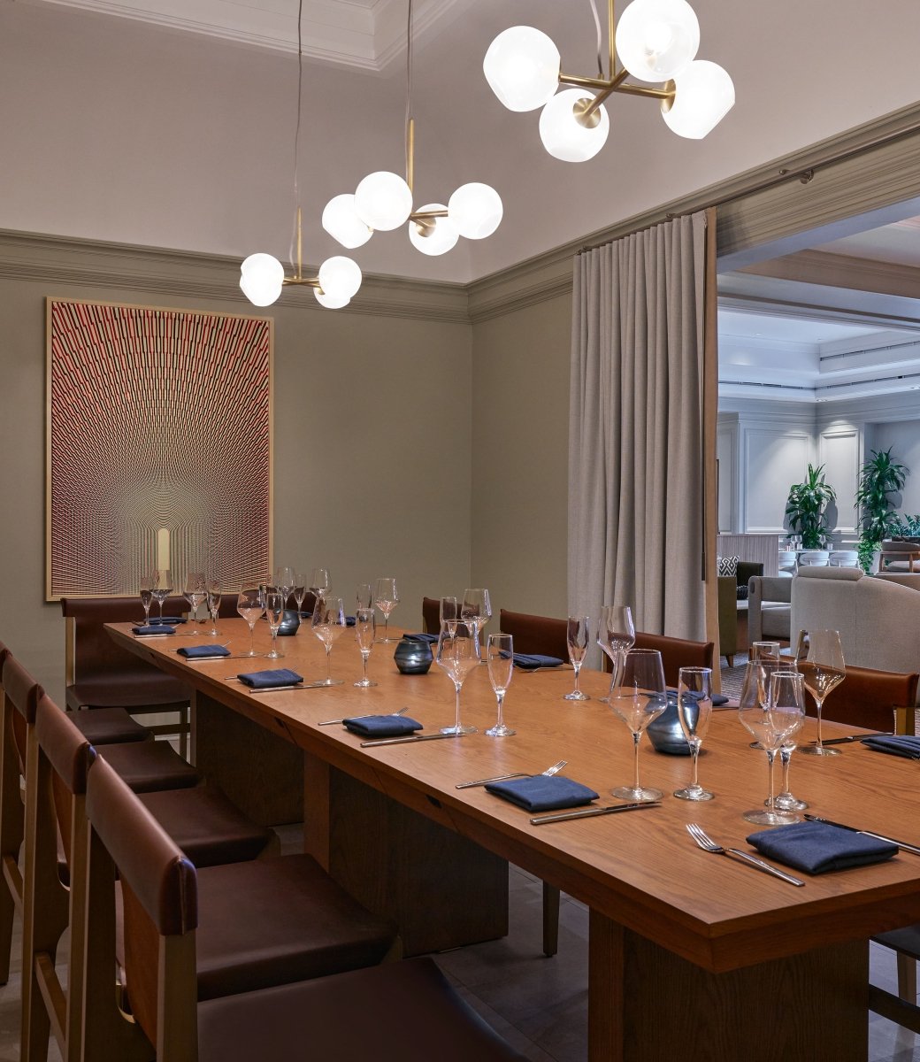 A private dining room with a long table set up for service at the Camby