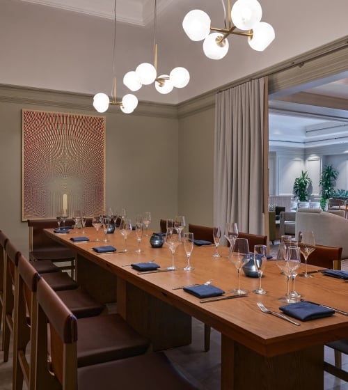 A private dining room with a long table set up for service at the Camby