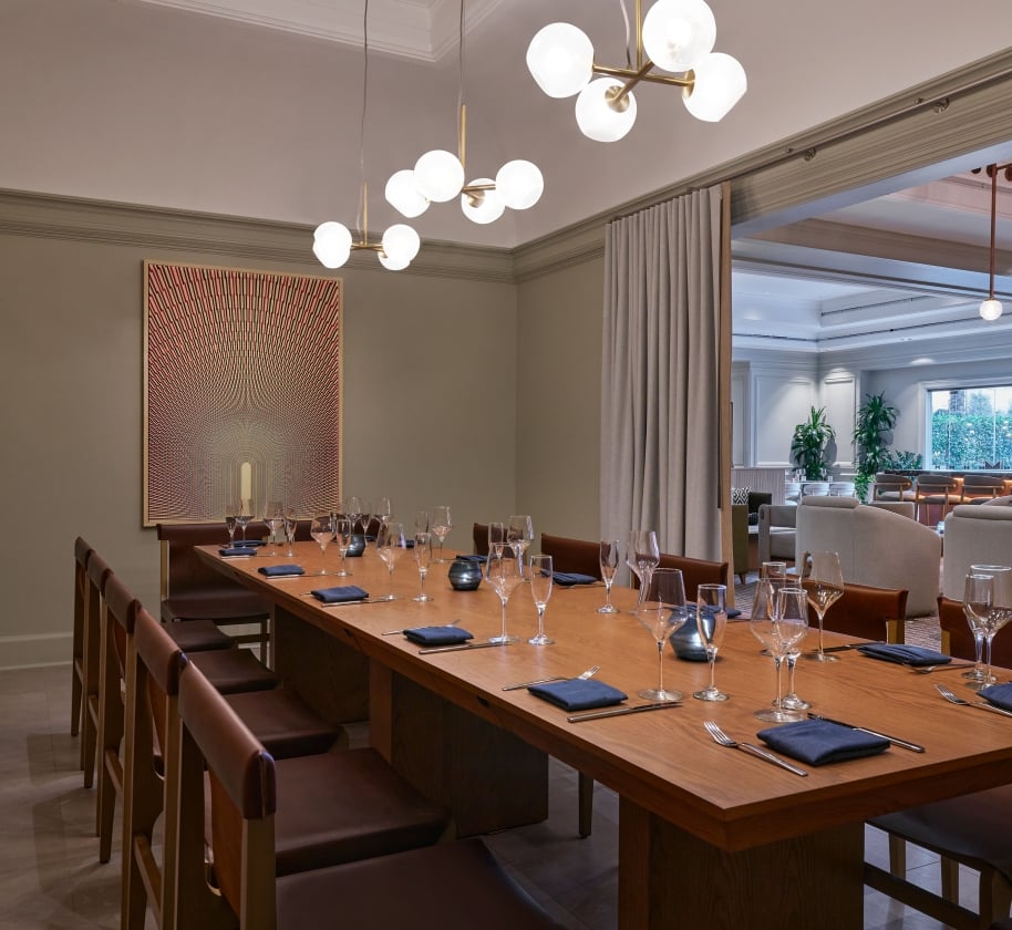 A private dining room with a long table set up for service at the Camby