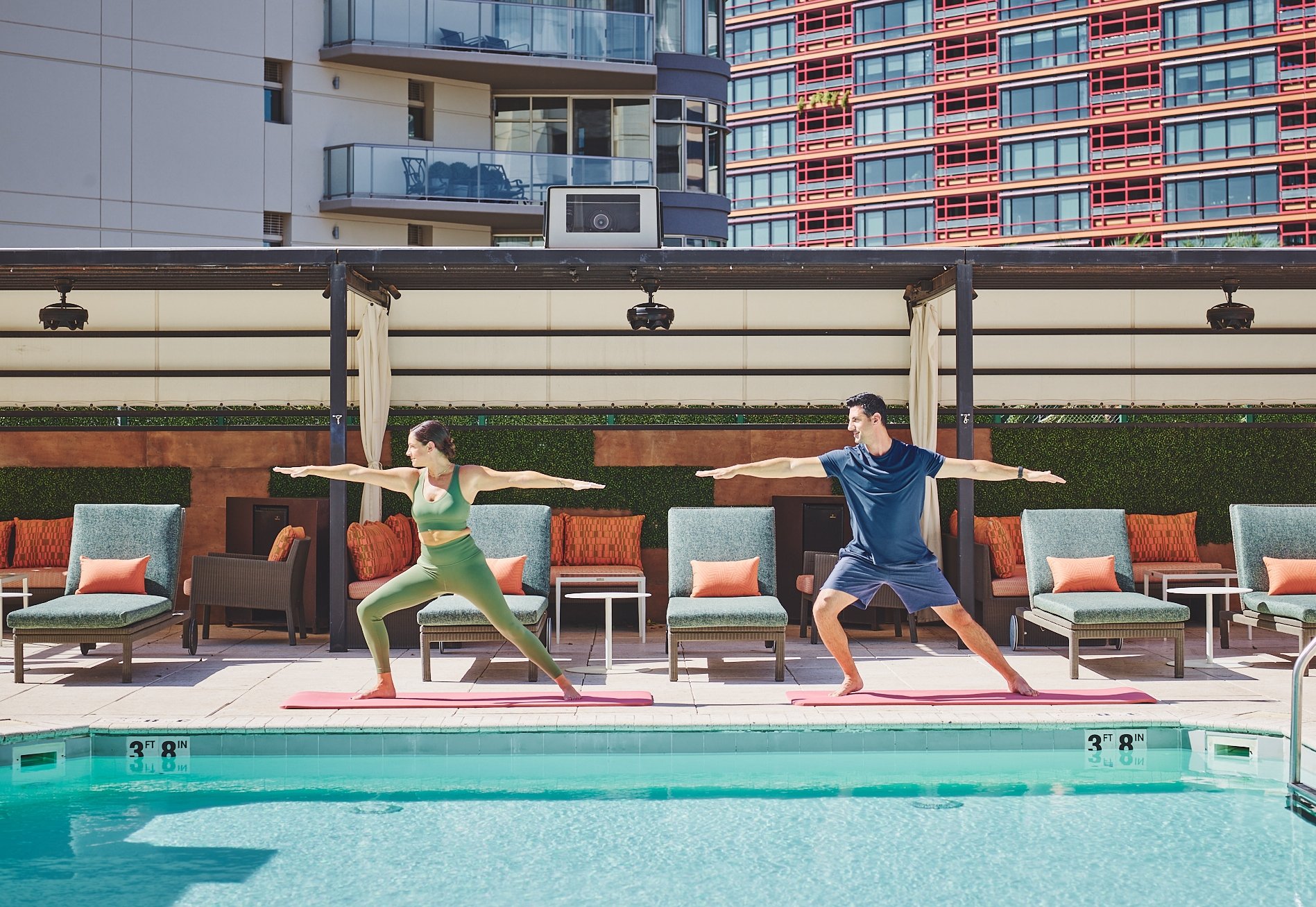 Two people doing yoga poolside