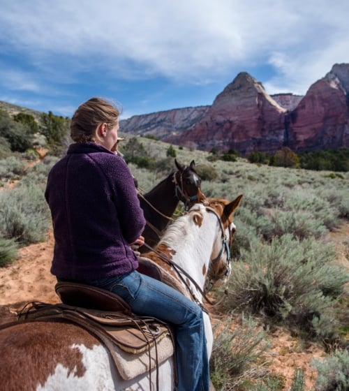 A woman riding a horse int he outback of Arizona